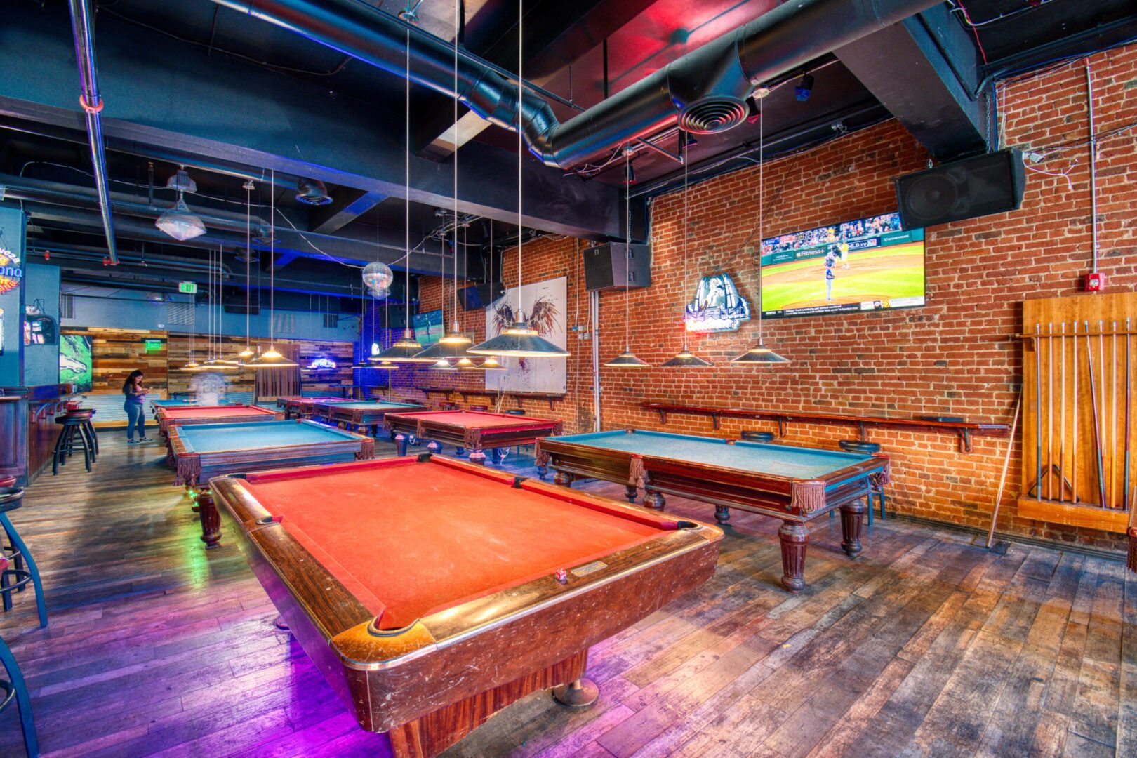 A room with several pool tables and benches.