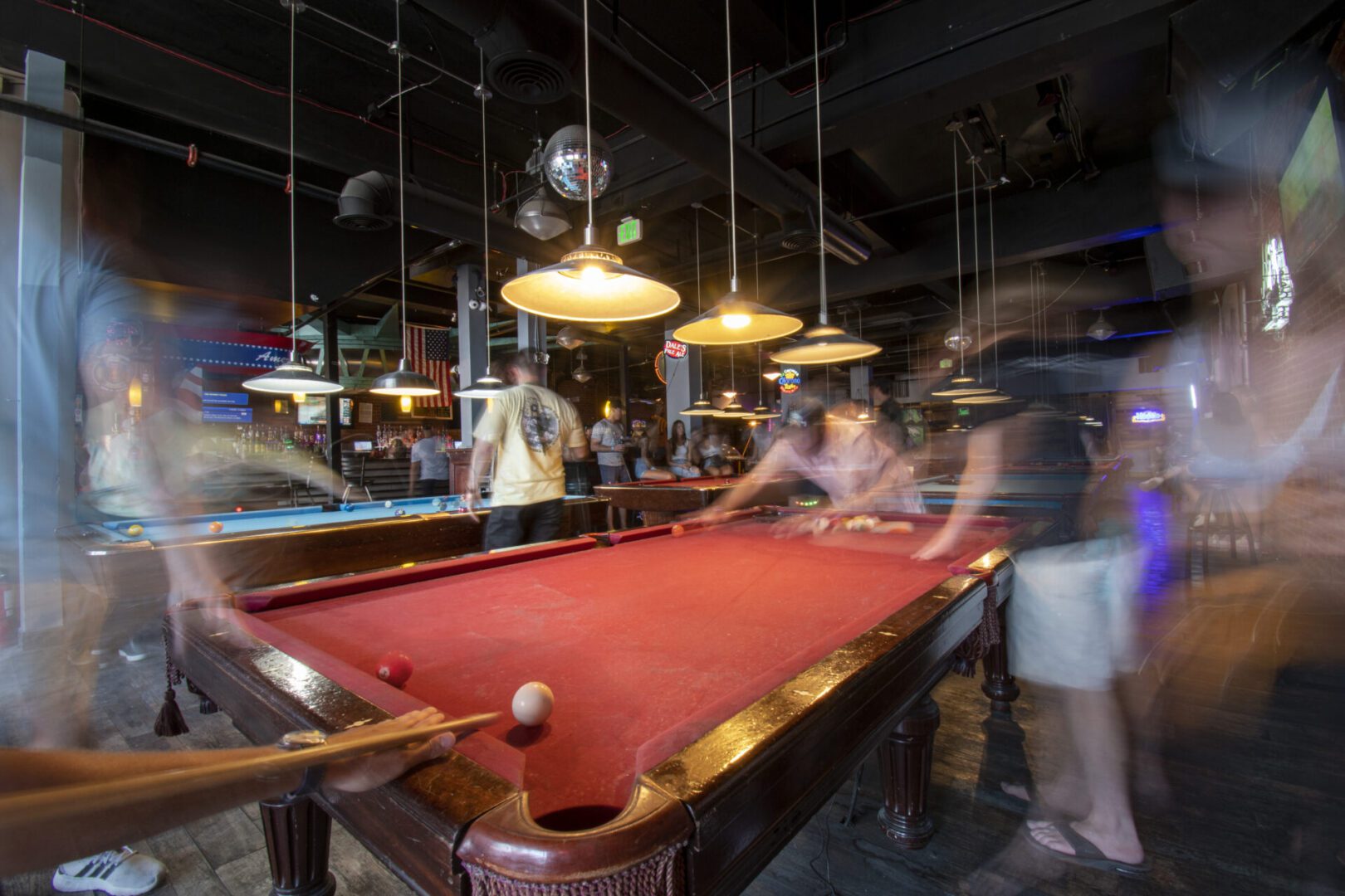 A group of people playing pool in a bar.