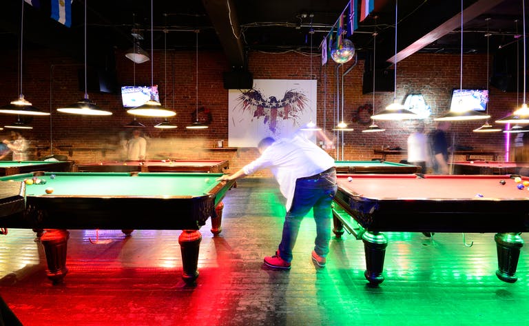 A man playing pool in a room with lights.