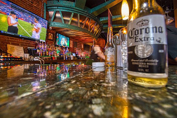 A bar with a bottle of corona extra and glasses