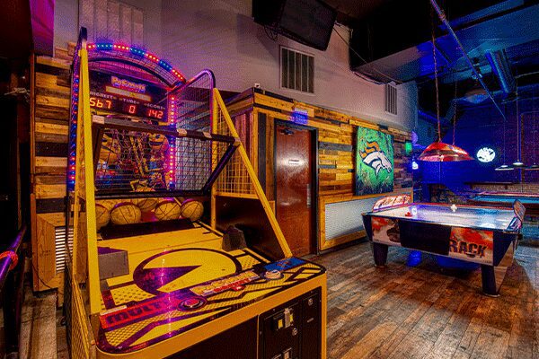 A room with several arcade games and tables.