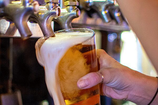 A person holding onto a glass of beer