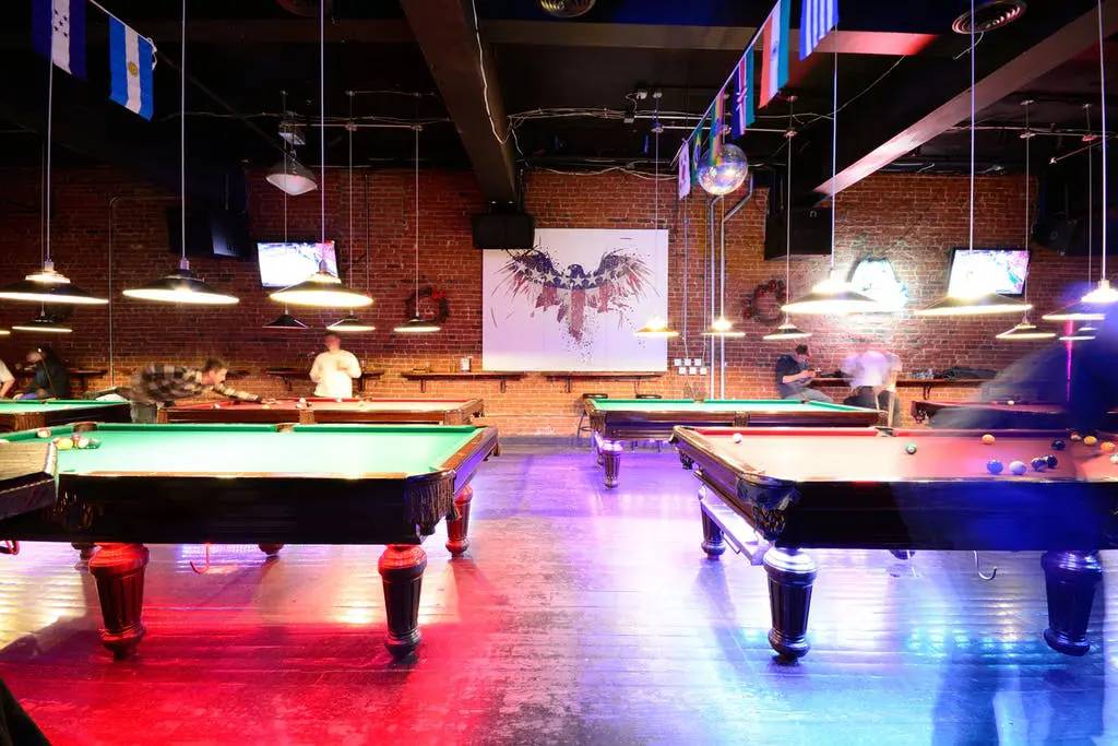 A room with three pool tables and two lights